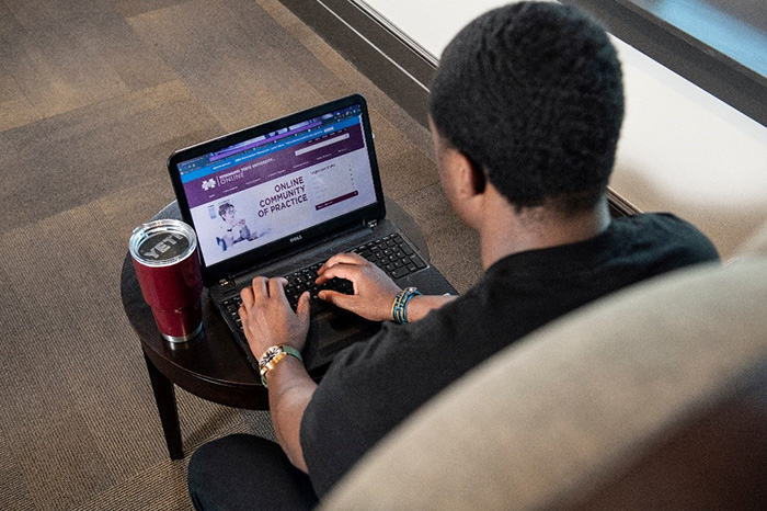Student typing on their laptop with MSU Online website on screen