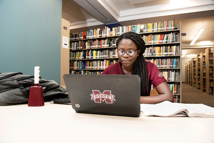 A student at Mississippi State University studying on her laptop in a library