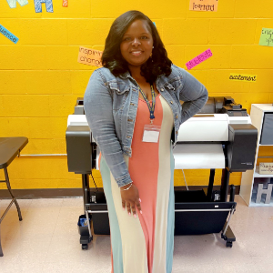 Porsche Chambers stands in front of a printer in her classroom. 