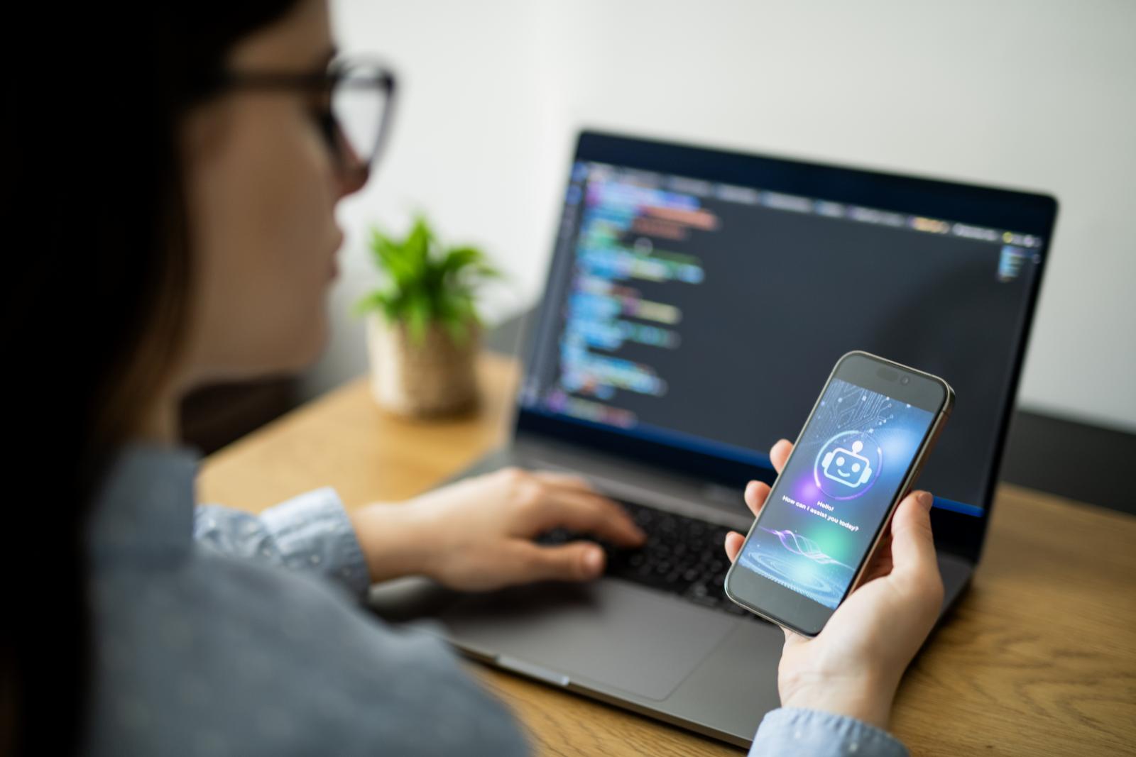 Person at computer interacting with A.I. on phone