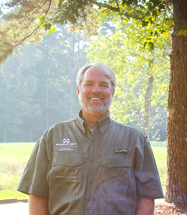 Eric Clark standing for a posed picture with the sun shining into the photo